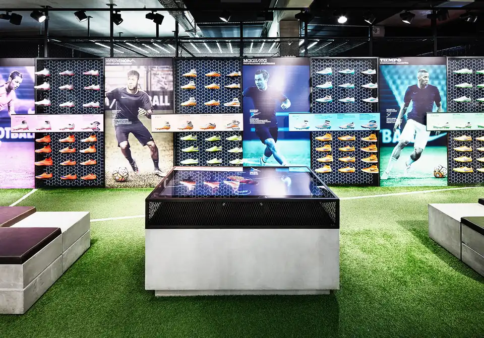 The RFID product table on turf in the Nike football flagship, boot walls and player imagery behind it